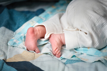 Newborn baby's wrinkled and cracked feet resting on a bed, showcasing delicate infant skin details