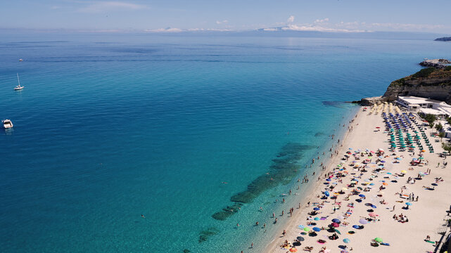 Aerial view of tourists enjoying crystal clear turquoise water and white sand beach at Tropea, Italy