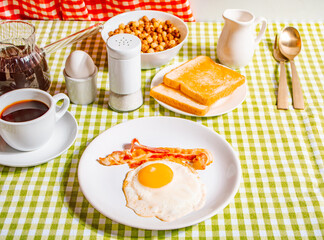 Fried egg with roasted bacon, black coffee, toasts on yellow background. Retro American breakfast. Hard shadow.