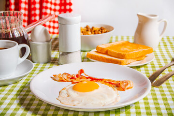 Fried egg with roasted bacon, black coffee, toasts on yellow background. Retro American breakfast. Hard shadow.