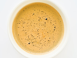 Cappuccino creamy milk foam texture in a white cup. Top view on white background. Design element.