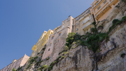 Low angle view of colorful houses standing on the cliff in Tropea, Calabria, with blue sky