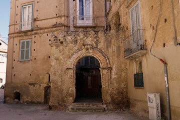 Weathered facade of a historic building in Tropea, Italy, featuring an arched doorway and traditional architectural details