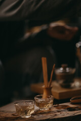 A cozy tea ceremony setting with glass teacups, wooden tray, and warm lighting. Calm atmosphere, mindfulness, and traditional tea preparation in a modern interior.