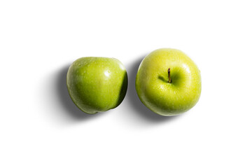Two fresh green apples on white background with hard shadows. Crisp texture and vivid color are emphasized by direct lighting, showcasing the simplicity and freshness of the isolated fruit.