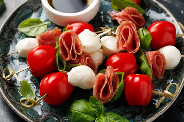 Mini skewer appetizers with salami, mozzarella and tomatoes. Healthy antipasto skewer.