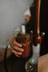 Refreshing cocktails with mint and ice served beside a hookah, surrounded by aromatic smoke. Cozy lounge atmosphere, perfect for a stylish evening or night out.