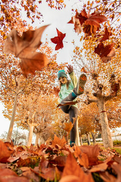 Woman playfully kicking autumn leaves in a park. Lifestyle. Autumn.