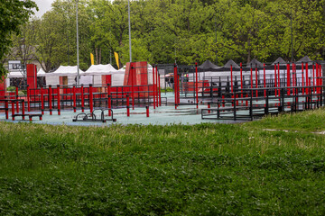 Sports ground with outdoor exercise equipment. Green trees around