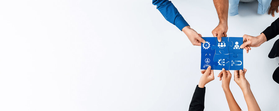 Diverse hands come together to hold a blue chart adorned with business icons and graphs, symbolizing teamwork and collaboration in a professional setting. Amity