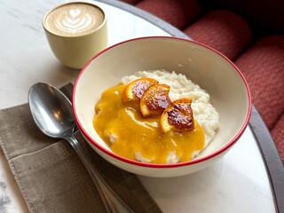 Bowl of Rice Porridge Topped with Caramelized Oranges and Orange-Vanilla Sauce. Contemporary Vegetarian Breakfast Out Theme. Manual Phone Photography, Selective Focus, No AI