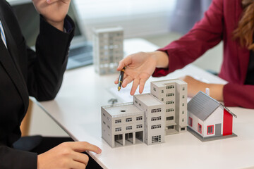 Inside a real estate office a real estate agent is presenting a condominium unit for sale to a client and offering a valuable promotion to entice the client to purchase their own property. copy space