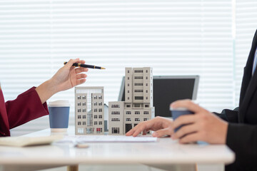 Inside a real estate office a real estate agent is presenting a condominium unit for sale to a client and offering a valuable promotion to entice the client to purchase their own property. copy space