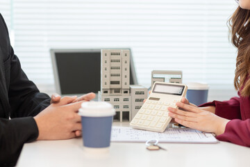 Inside a real estate office a real estate agent is presenting a condominium unit for sale to a client and offering a valuable promotion to entice the client to purchase their own property. copy space