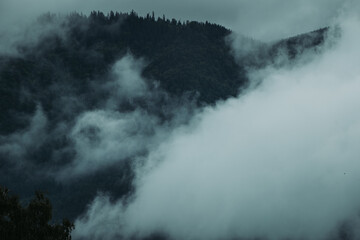 Atmospheric landscape with fog-covered hills and clouds after rain
