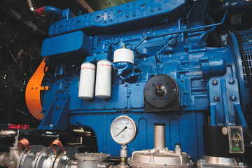 Large blue diesel engine generator with stainless steel pipes and manometers