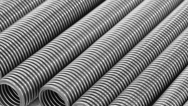 Row of stainless steel corrugated high pressure pipes in silver color. The pipes are long and thin. Mechanical industrial concept background
