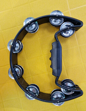 black half moon tambourine on yellow background