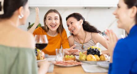 Girlfriends drinking wine and having conversation over dinner at a house party