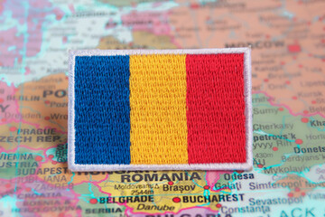 Eco-friendly embroidered Romanian flag positioned on a world map at the Eastern European region....