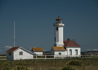 Point Wilson Lighthouse surrounded by grass field and mesh fence