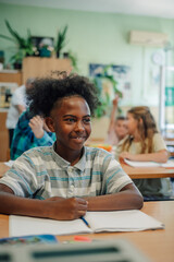 Smiling pupil sitting at desk listening to teacher in classroom