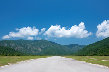 serene asphalt road winding through lush green meadows under clear bright sky