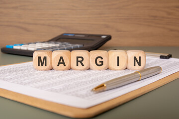 wooden blocks spelling MARGIN on financial documents with a pen and calculator in the background