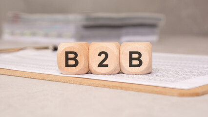 wooden cubes spelling B2B on a document clipboard, symbolizing business-to-business concepts
