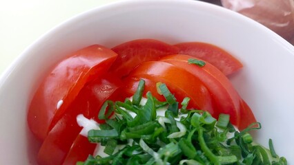 Fresh Salad Bowl With Sliced Tomatoes and Chopped Onions Garnished With Green Herbs