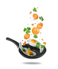 Flying eggs, parsley and spices above a frying pan on light background