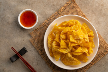 Crispy wonton,Deep Fried Crispy Prawn Wontons sheet on white plate with Sweet Chili Sauce.asian snack food.Top view.