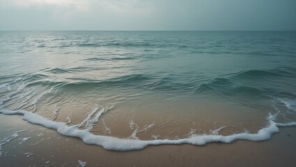 Gentle waves on the beach with calm sea and cloudy sky. Coastal scene, tranquil ocean, and sandy shore.