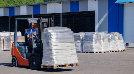 Forklift transports rolls of finished polyethylene bags in plastic packaging warehouse