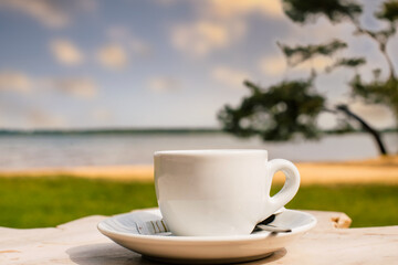 Cup of coffee or espresso placed on a wooden table facing the sea