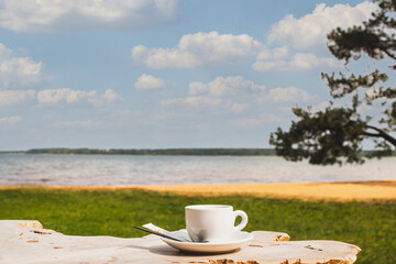 Cup of coffee or espresso placed on a wooden table facing the sea