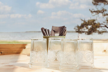 Table de restaurant ou de camping avec des verres posée sur une table en bois face a la mer