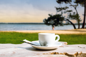 Cup of coffee or espresso placed on a wooden table facing the sea