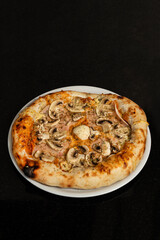 A top view of Pizza capricciosa with cherry tomatoes,greens and garlic on a wooden table