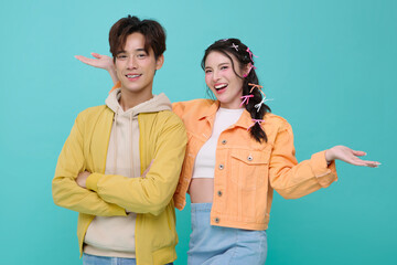 Happy young Asian teen couple welcome presenting or showing open hand palm isolated on blue background.