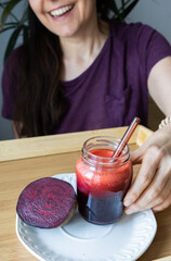 Beetroot Smoothie in the Foreground with Woman in the Background About to Drink