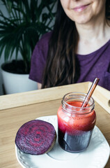 Beetroot Smoothie in the Foreground with Woman in the Background About to Drink
