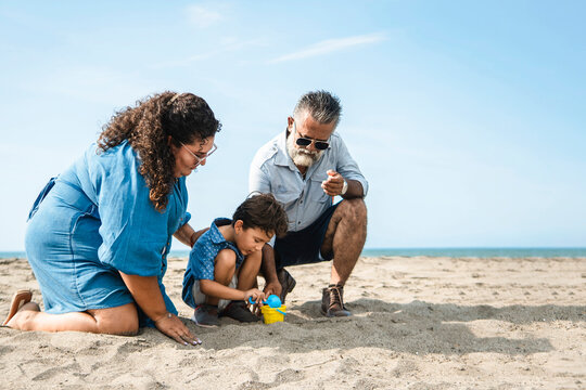 Happy family playing on the beach building sandcastles