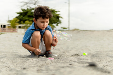 Child having fun making soap bubbles on the beach