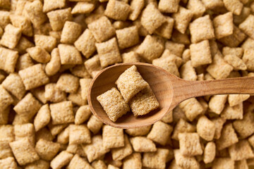 wooden spoon of delicious corn pillows above tasty corn pads as background. Top view.