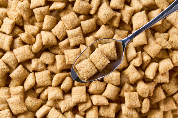 corn pads in a metal spoon of above corn puffs as background. Copy space for text.