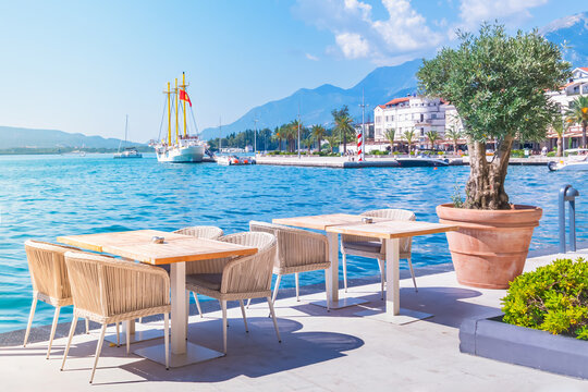 Tivat,Montenegro waterfront dining experience in Boka Bay with stunning Adriatic views and serene ambiance,featuring an inviting outdoor cafe restaurant,clear blue waters,majestic mountains and yachts