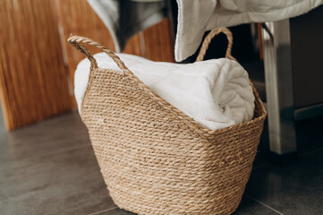 Wicker basket with white towels in a bright modern spa salon interior close-up