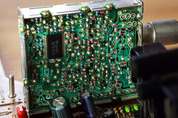 An old circuit board with intricate patterns of green and metallic components. Various resistors,...