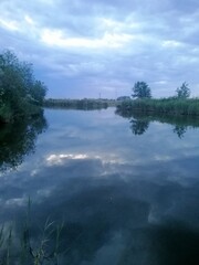 vertical photo Twilight moment over calm river with soft natural light and silhouettes of distant trees. Dusk atmosphere with quiet water and moody clouds suggesting end of day and serenity. concept